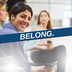 An image of people at a meeting with a purple banner that says "Belong."