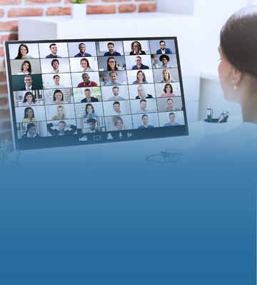 A woman on her computer looking at a virtual meeting, fading into a blue block