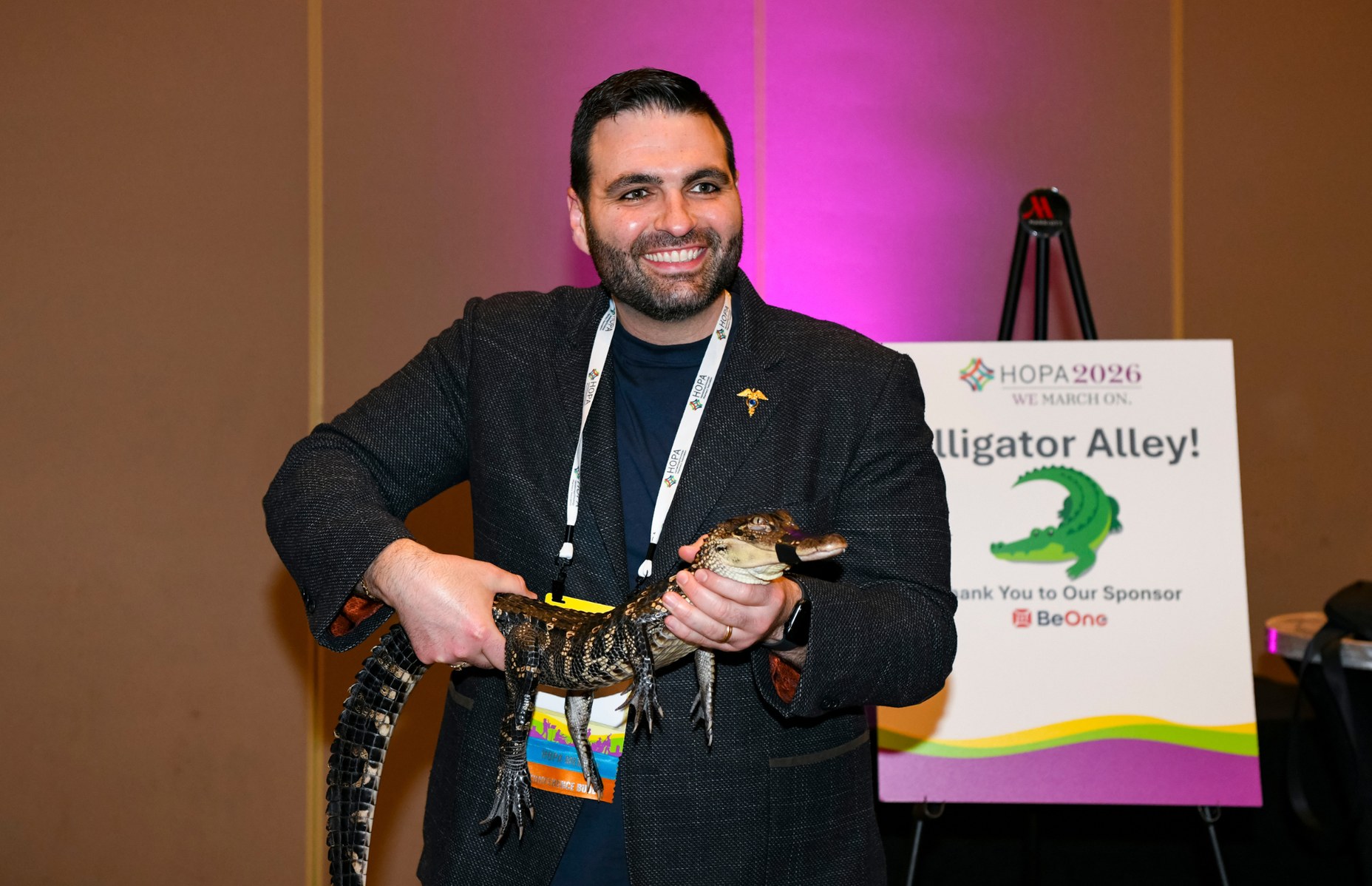 A man holding a gator at the closing reception at HOPA 26