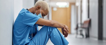 Nurse sitting in hospital hallway resting against a wall