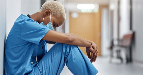 Nurse sitting in hospital hallway resting against a wall
