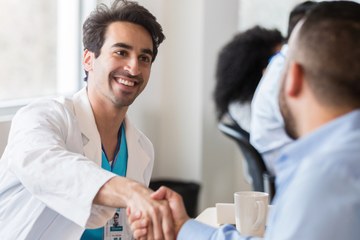 A doctor shaking hands with a person during a meeting