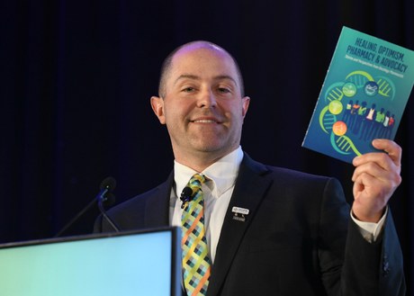 Robert Mancini speaking at HOPA 2026 while holding a copy of the HOPA Book of Letters