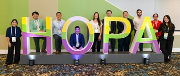 A group of HOPA Annual Conference 2026 attendees gathered around a colorful HOPA sign