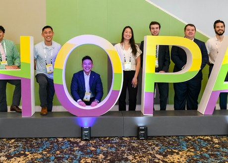 A group of HOPA Annual Conference 2026 attendees gathered around a colorful HOPA sign