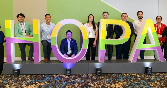 A group of HOPA Annual Conference 2026 attendees gathered around a colorful HOPA sign