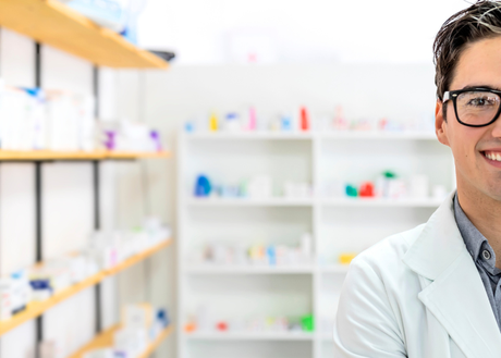 Young man in a pharmacist coat at work