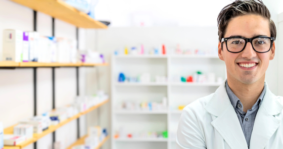 Young man in a pharmacist coat at work